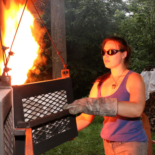 Jessikah flipping the coals in the anagama.